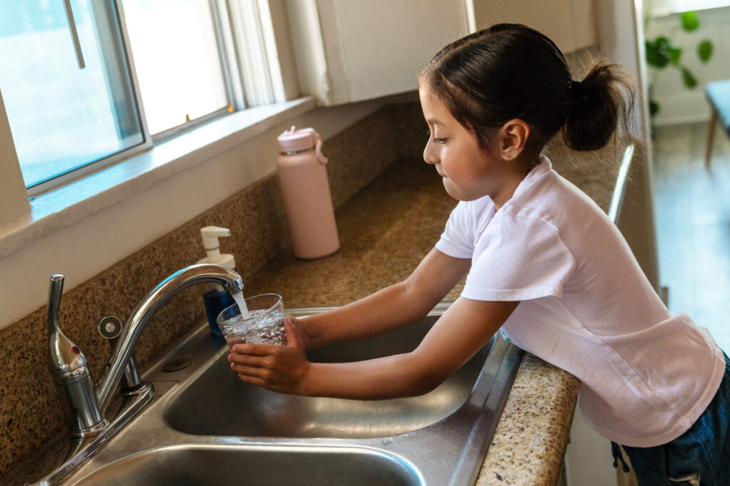 girl pouring water from sink to cup